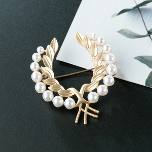 Détail de la broche couronne de laurier dorée mate avec perles et fermoir épingle