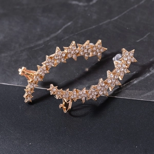 Detail of gold star ear cuffs with sparkling rhinestones on a dark marble surface