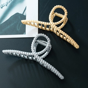Detail of twisted metal hair claws in gold and silver finish with textured spiral design