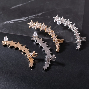 Star-shaped rhinestone ear crawlers set in gold and silver plating on dark background