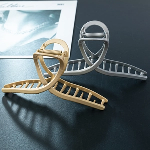 Matte finish cross-line metal hair claws in gold and silver on a minimalist background
