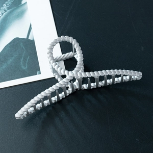 Large silver-colored twist textured metal hair claw clip for women on a dark background