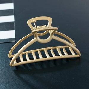 Macro detail of matte gold alloy hair claw clip showing polished curves and sturdy metal teeth