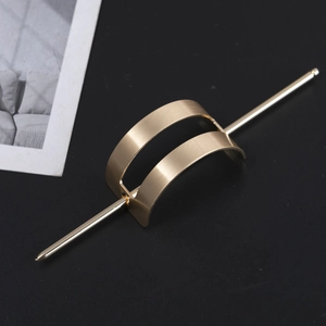 Detailed macro view of golden brushed metal hair pin with hollow double-arch design