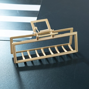 Detail der goldenen rechteckigen hohlen Haarklammer mit mattem Finish und Metallfeder