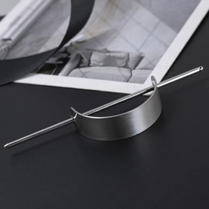 Detail of matte silver metal hair stick with brushed texture on a black background