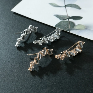 Vue macro de boucles d'oreilles grimpeuses dorées et argentées avec strass rectangulaires