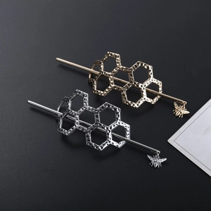 Golden and silver metal honeycomb hairpins with bee charms on dark background