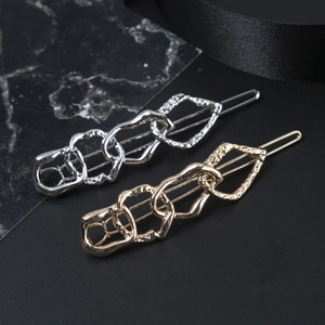 Detailed macro view of gold and silver irregular chain hair clips with hammered metal texture