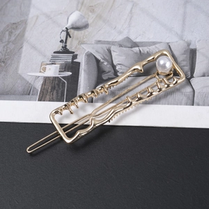 Detailed close-up of a gold alloy rectangular hair clip with wave texture and white pearl
