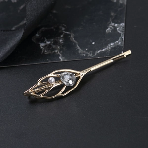 Détail de la pince à cheveux feuille dorée évidée avec cristal et ornement de perle blanche