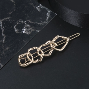 Golden geometric interlocking chain hair clip with textured metal finish on black silk