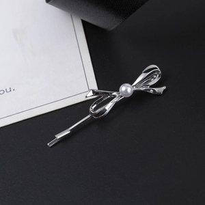Barrette nœud argentée avec perle blanche sur un fond élégant et minimaliste