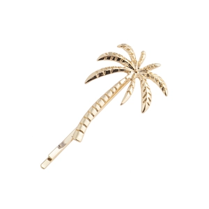 Macro detail of a golden palm tree hair clip with glossy metallic texture and palm leaf design