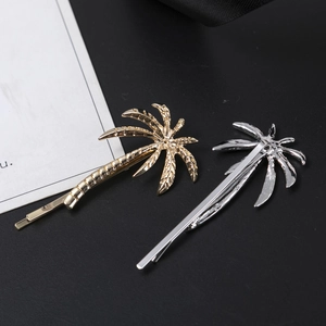 Detail view of tropical palm tree hair clips set in polished gold and silver alloy