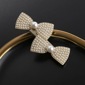 Eleganter goldener Haarschmuck in Schleifenform mit weißen Perlen auf Schwarz