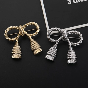 Detailed view of elegant bow brooches with metal tassels in gold and silver finish