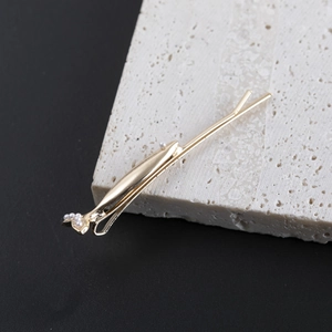 Elegant gold fish bone hair clip with white pearls on a natural white stone base
