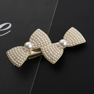 Eleganter goldener Haarclip mit Perlen-Schleifen-Design auf schwarzem Display-Hintergrund