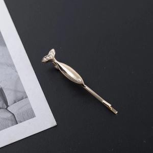 Detailed view of a golden fish-shaped hair clip with elegant pearl accents on the tail