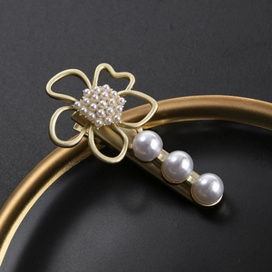Elegante pasador de flor dorada con perlas blancas y diseño de pétalos calados