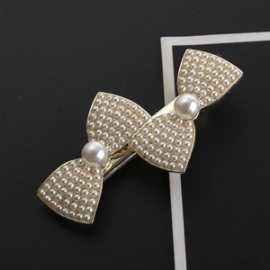 Eleganter goldener Haarschmuck mit Schleifendesign und weißen Perlenverzierungen im Detail