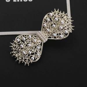 Elegant gold butterfly hair clip with intricate filigree pattern and white pearls