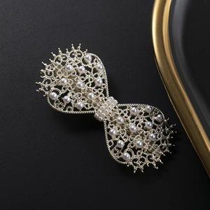 Elegant gold hollow butterfly hair clip with white pearls on a minimalist dark background