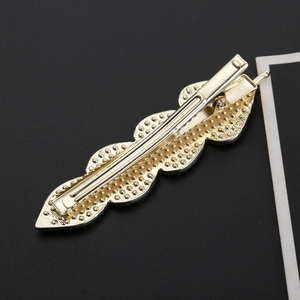 Eleganter goldener Haarclip in Blattform mit strukturierter Oberfläche auf schwarzem Grund