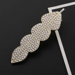 Eleganter goldener Haarclip in Blattform mit weißen Perlen auf schwarzem Hintergrund