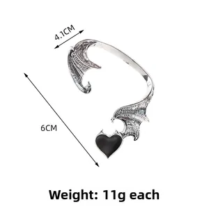 Detail view of retro dragon wing ear cuff with dimensions 6cm by 4.1cm and black heart charm