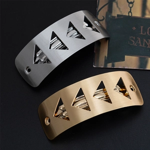 Detalle de pinzas de metal cepillado con recortes triangulares en acabado dorado y plateado