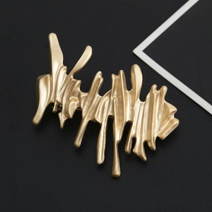 Golden irregular metal hair clip with matte liquid lava texture on black background