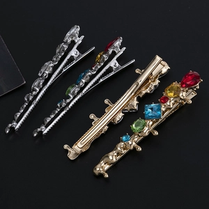 Lot de quatre barrettes à cheveux en métal fluide avec cristaux colorés sur fond noir