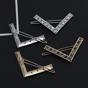Set of four vintage V-shaped metal hair clips with mixed crystals on a black background