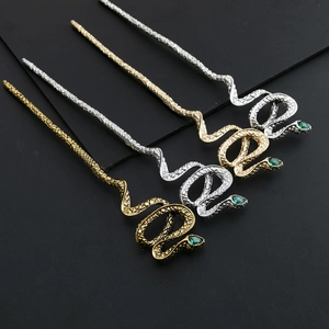 Détail d'épingles à cheveux serpent avec pierres vertes en finition or et argent