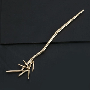 Close-up of golden bamboo joint hair stick with realistic leaves and metal texture