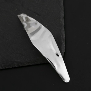 Minimalist geometric silver hair clip with brushed lava texture on black stone surface