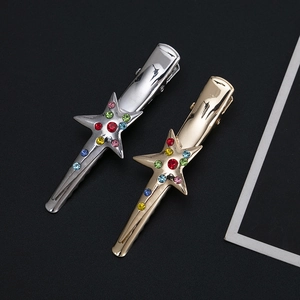 Polished star hair clips in gold and silver with colorful rhinestones set on a black background