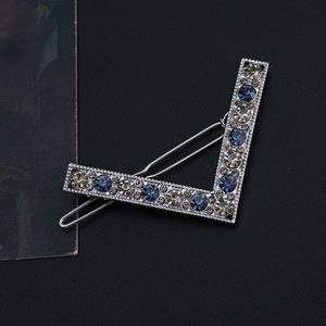 Detailed macro view of V-shaped silver alloy hair clip with blue and champagne rhinestones