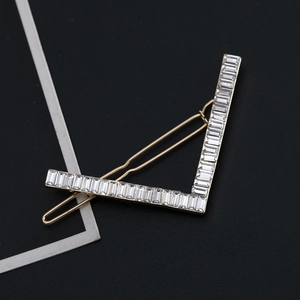 Detailed macro view of the V-shaped geometric gold hair clip with clear rhinestones