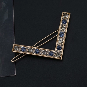 Detailed macro view of V-shaped gold hairpin with blue and grey crystal stones