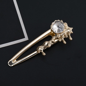 Détail d'une pince à cheveux dorée texture lave avec une grande pierre de zircon ronde