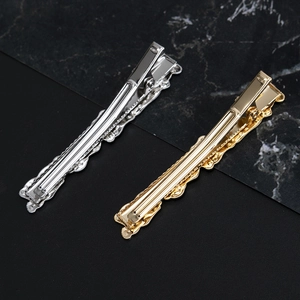 Textured gold and silver alloy duckbill hair clips with wavy镂空 edges on marble background