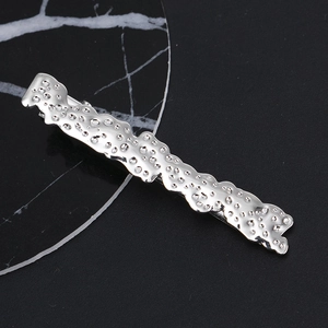 Detailed view of hammered silver alloy hair clip with liquid metal texture and wavy edges