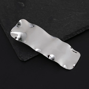 Minimalist silver wavy irregular hair clip with polished mirror finish on dark stone
