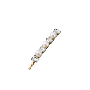 Detail of a gold metal hair clip featuring white pearls and clear oval crystals