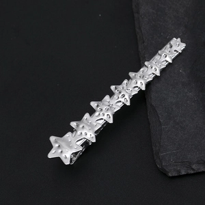 Détail de la pince à cheveux étoile en argent avec finition mate sur fond de pierre sombre