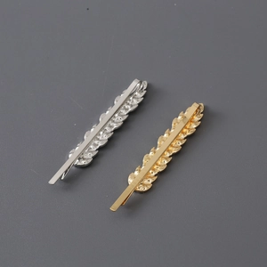 Detail of gold and silver feather hair clips with leaf textures and sturdy metal clip backings