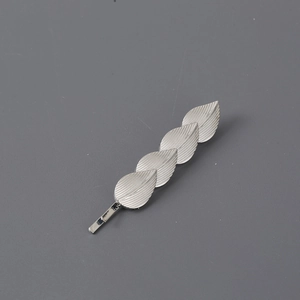 Minimalist silver metal leaf hair clip with brushed texture on a matte grey background